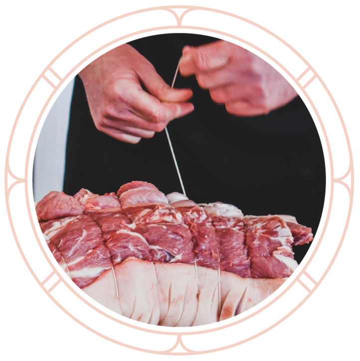 Boucher ficelant un rôti de porc en atelier