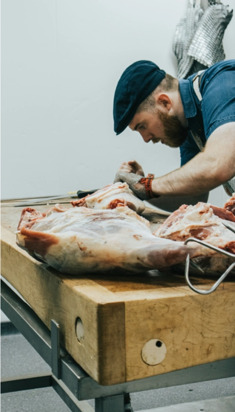 Boucher préparant une pièce de viande fraîche à Massieux